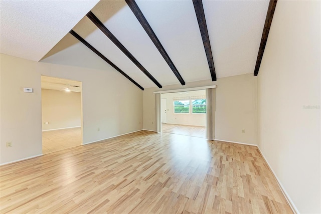 empty room featuring lofted ceiling with beams and light hardwood / wood-style floors