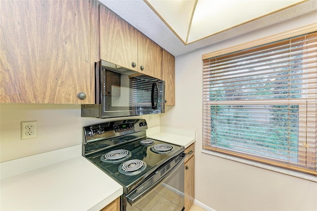 kitchen with tile patterned floors, black appliances, and a textured ceiling