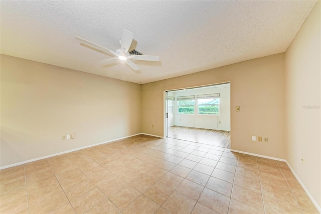 empty room with light tile patterned floors, a textured ceiling, and ceiling fan