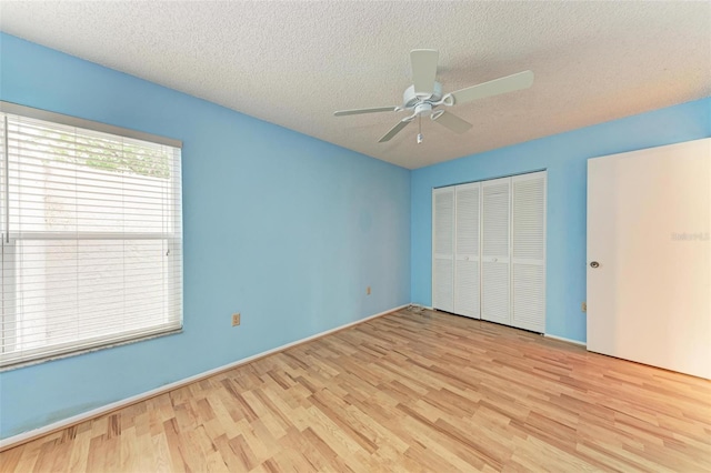 unfurnished bedroom with a closet, a textured ceiling, light hardwood / wood-style floors, and ceiling fan