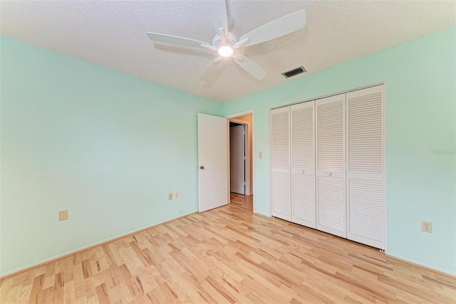 unfurnished bedroom featuring ceiling fan, a closet, a textured ceiling, and light wood-type flooring