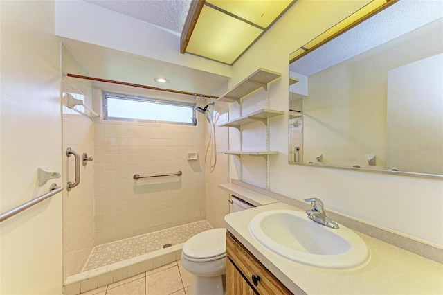 bathroom with tile patterned floors, a textured ceiling, vanity, tiled shower, and toilet