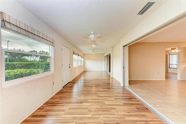 hallway featuring light hardwood / wood-style flooring and a textured ceiling