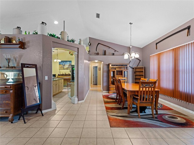 tiled dining space with lofted ceiling and a notable chandelier