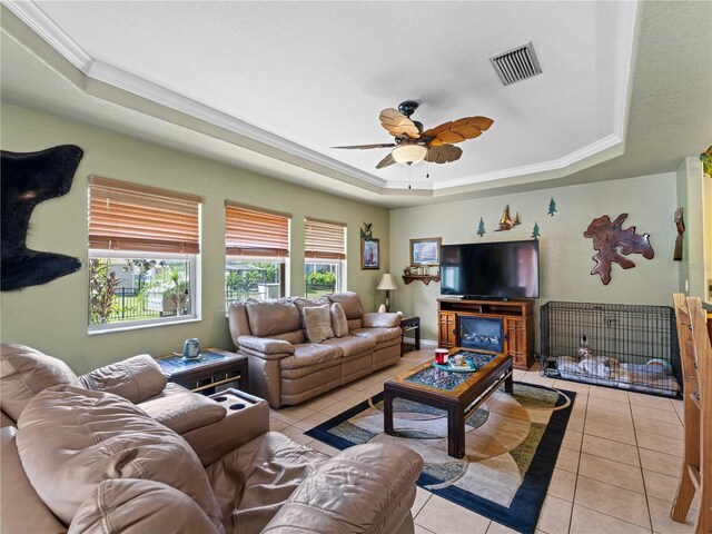 tiled living room featuring a tray ceiling, crown molding, and ceiling fan