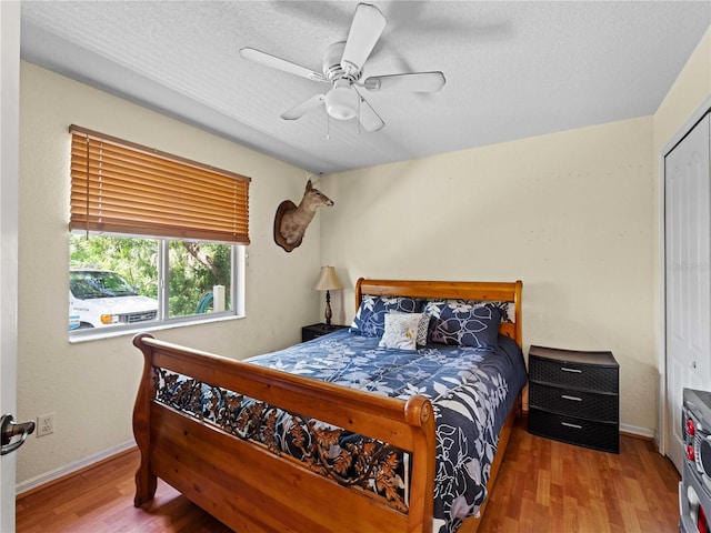 bedroom with a textured ceiling, a closet, ceiling fan, and hardwood / wood-style floors