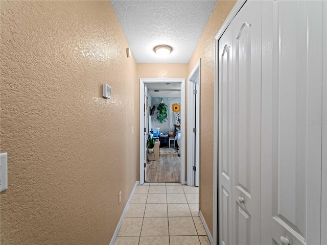 hallway with a textured ceiling and light tile patterned floors