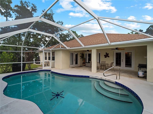 view of pool featuring glass enclosure, ceiling fan, and a patio