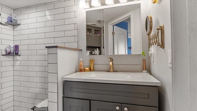 full bath featuring a tile shower, vanity, and visible vents