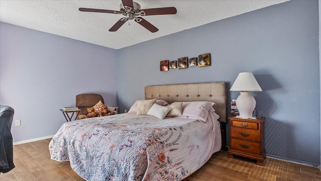 bedroom with ceiling fan, a textured ceiling, and hardwood / wood-style floors