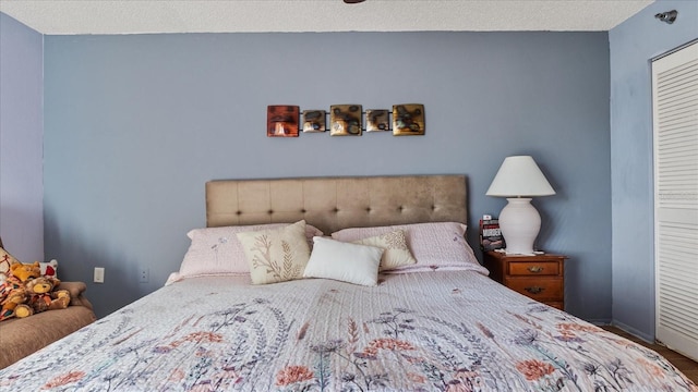 bedroom featuring a textured ceiling, wood finished floors, a closet, and baseboards