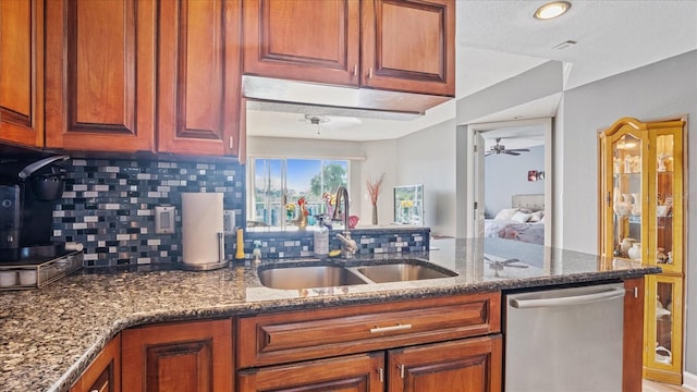 kitchen featuring decorative backsplash, dark stone countertops, ceiling fan, stainless steel dishwasher, and sink