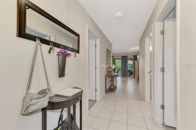 hallway with a textured ceiling and light tile patterned flooring