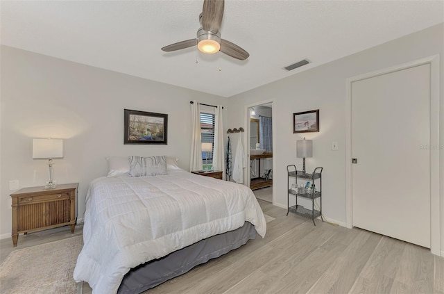 bedroom with ceiling fan, ensuite bathroom, and light hardwood / wood-style floors