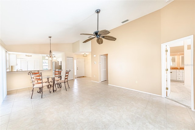 unfurnished dining area with ceiling fan with notable chandelier, high vaulted ceiling, and light tile patterned floors