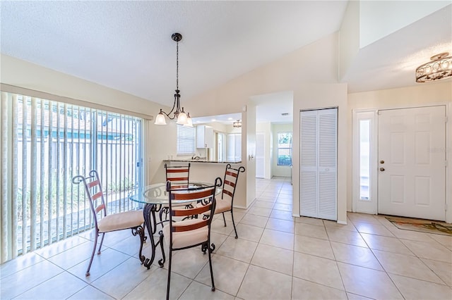 dining space featuring lofted ceiling, a notable chandelier, light tile patterned floors, and a textured ceiling