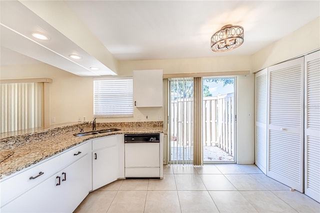 kitchen featuring white dishwasher, light stone counters, white cabinetry, sink, and light tile patterned flooring