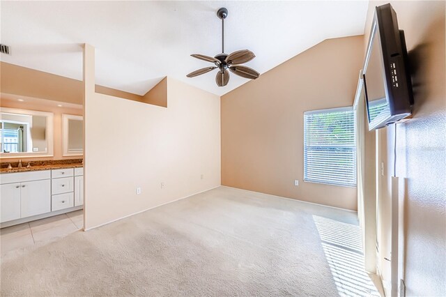 unfurnished living room featuring vaulted ceiling, light colored carpet, plenty of natural light, and ceiling fan