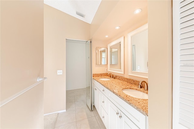 bathroom with a textured ceiling, vanity, vaulted ceiling, and tile patterned floors