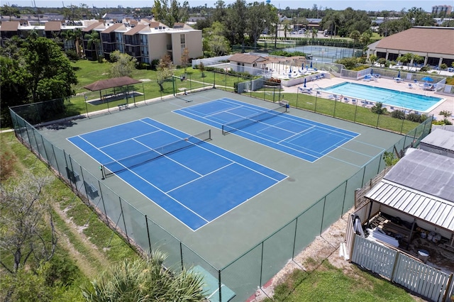 view of tennis court featuring a community pool and a water view