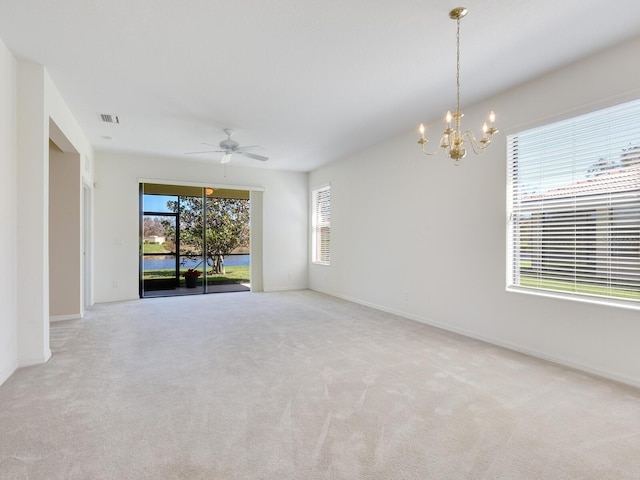 carpeted spare room with ceiling fan with notable chandelier