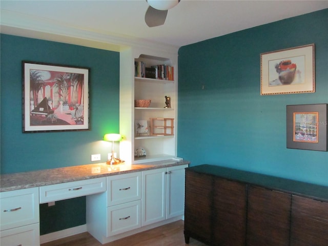 bar with white cabinetry, ceiling fan, built in desk, and hardwood / wood-style flooring