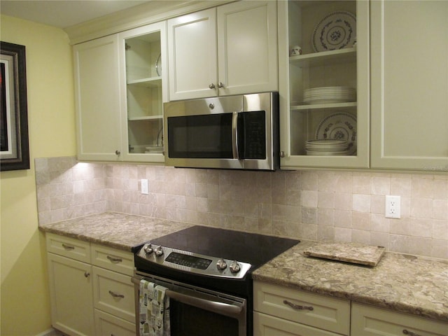 kitchen featuring decorative backsplash, light stone counters, and stainless steel appliances