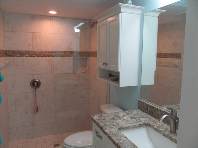 bathroom featuring vanity, toilet, and a tile shower