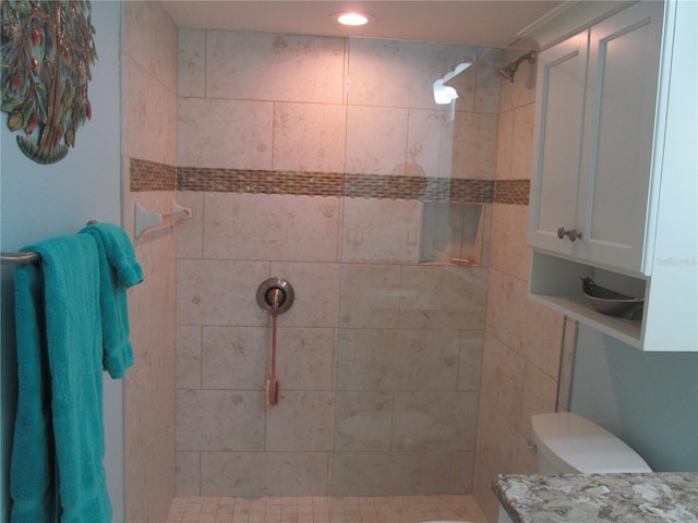 bathroom with a tile shower and toilet