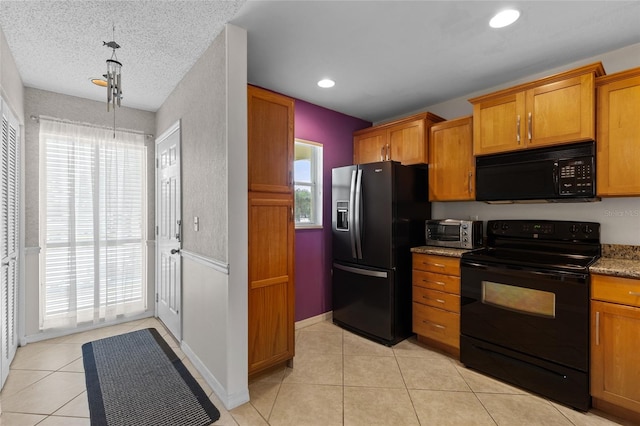 kitchen with a textured ceiling, black appliances, dark stone countertops, and light tile patterned floors