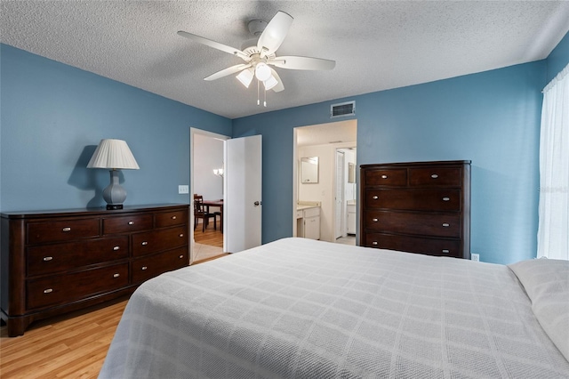 bedroom with ceiling fan, a textured ceiling, light wood-type flooring, and ensuite bathroom