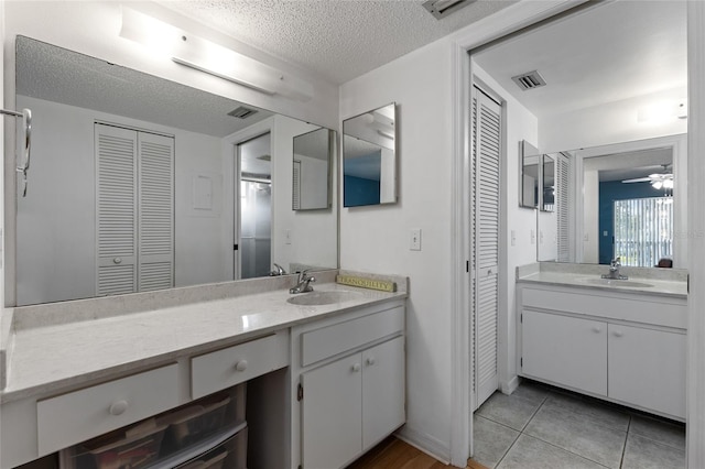 bathroom with tile patterned floors, ceiling fan, vanity, and a textured ceiling