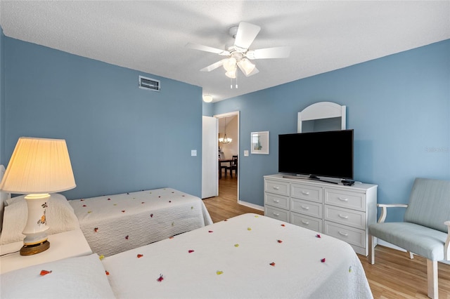 bedroom with light wood-type flooring, a textured ceiling, and ceiling fan