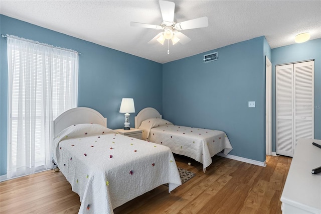 bedroom featuring ceiling fan, a textured ceiling, a closet, and light hardwood / wood-style floors