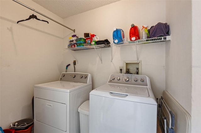 laundry area with washing machine and clothes dryer and a textured ceiling