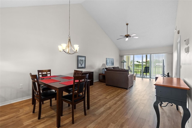 dining space featuring ceiling fan with notable chandelier, high vaulted ceiling, wood finished floors, and baseboards