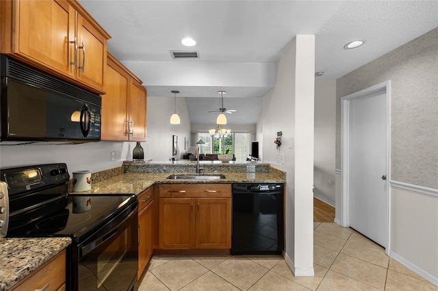 kitchen featuring stone countertops, brown cabinetry, a sink, and black appliances