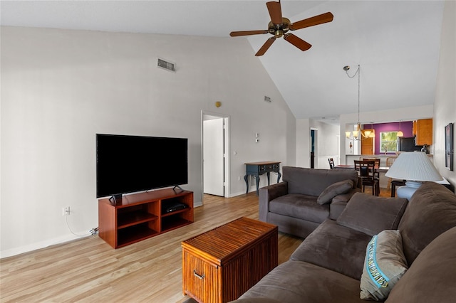 living area featuring high vaulted ceiling, visible vents, light wood finished floors, and ceiling fan with notable chandelier