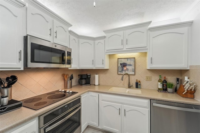 kitchen with tasteful backsplash, white cabinetry, sink, and stainless steel appliances