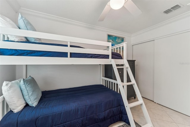 tiled bedroom with a closet, ceiling fan, and crown molding