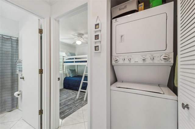 laundry room with stacked washer / dryer, ceiling fan, and light tile patterned floors