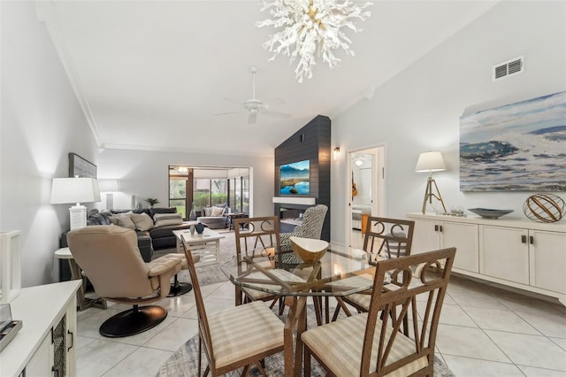 tiled dining space featuring ceiling fan with notable chandelier, crown molding, and high vaulted ceiling