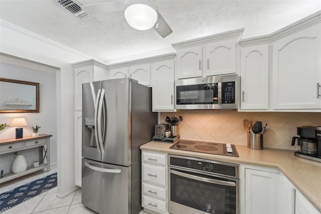 kitchen featuring decorative backsplash, a textured ceiling, appliances with stainless steel finishes, light tile patterned flooring, and white cabinetry