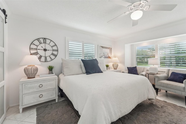 tiled bedroom featuring ceiling fan, a barn door, ornamental molding, and multiple windows