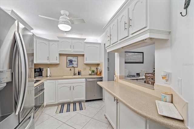 kitchen featuring a textured ceiling, stainless steel appliances, ceiling fan, sink, and white cabinetry