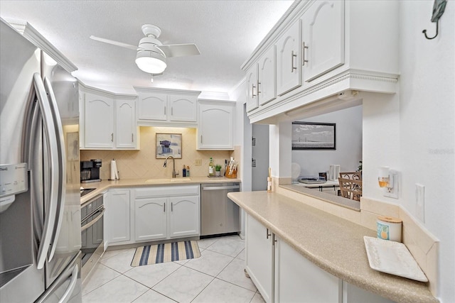 kitchen with white cabinetry, sink, stainless steel appliances, kitchen peninsula, and light tile patterned floors