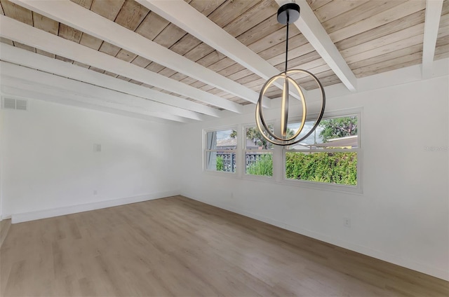 spare room with beamed ceiling, visible vents, wood finished floors, and baseboards