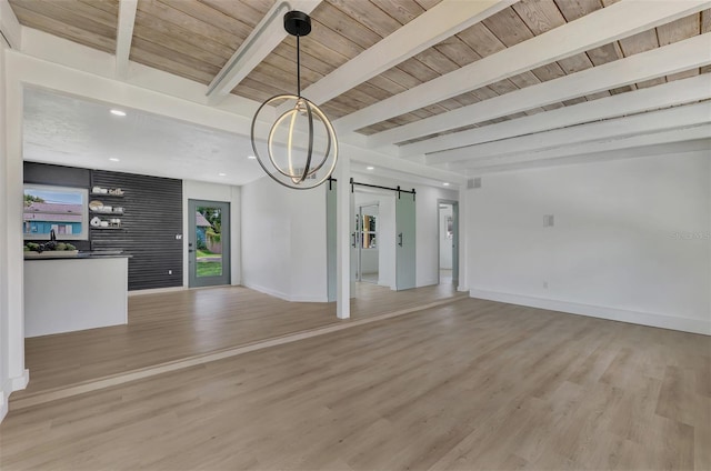 unfurnished living room featuring baseboards, beamed ceiling, a barn door, and light wood-style flooring