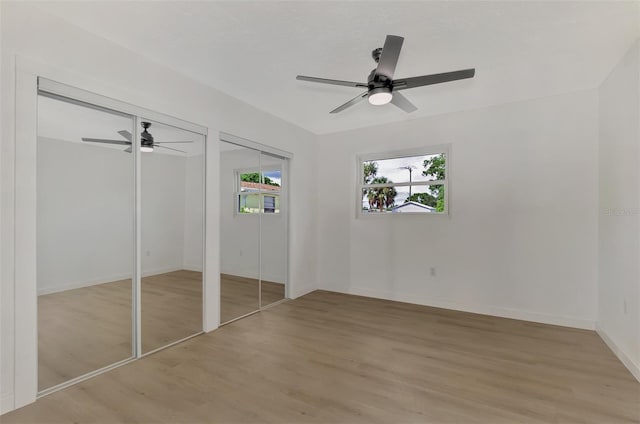 unfurnished bedroom featuring ceiling fan, two closets, and light hardwood / wood-style floors