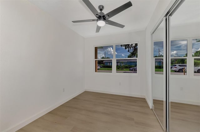 unfurnished bedroom with ceiling fan, a closet, light wood-type flooring, and multiple windows